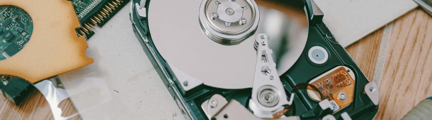Close-up of a disassembled hard drive showing internal components on a wooden table.