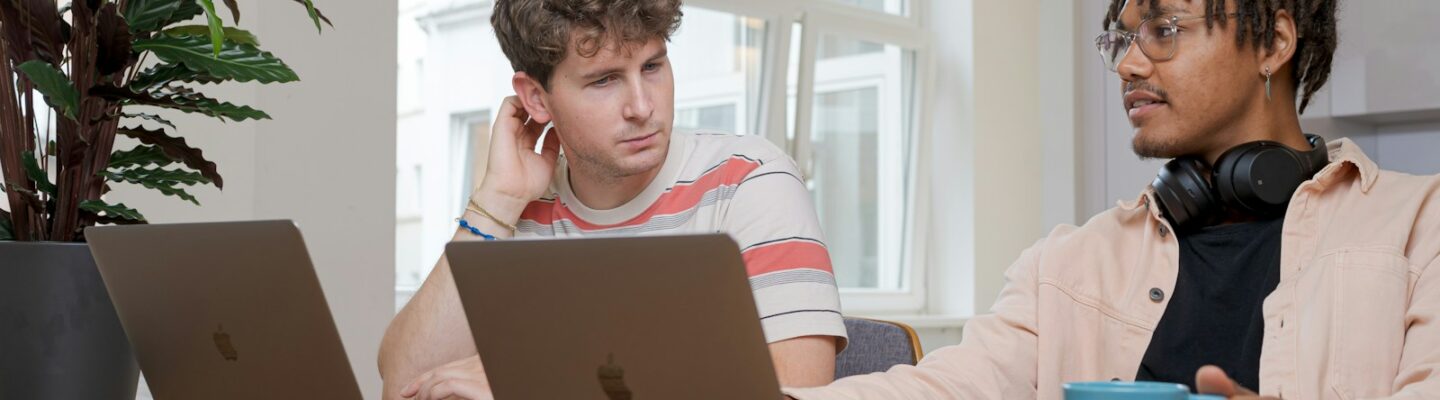 man and woman sitting at table using macbook
