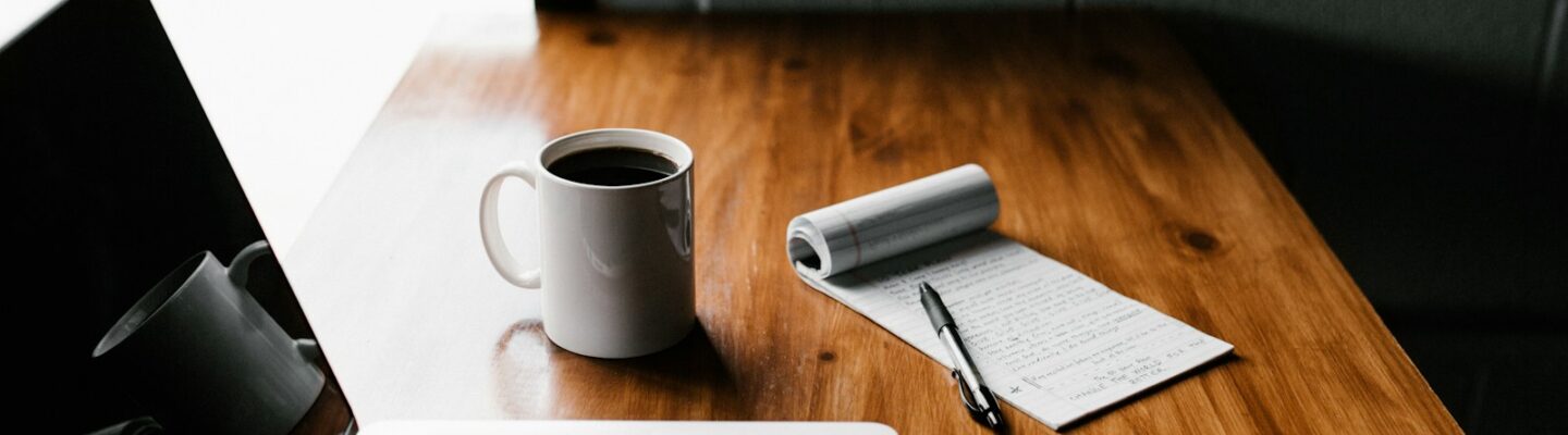 MacBook Pro, white ceramic mug,and black smartphone on table