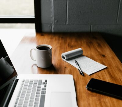 MacBook Pro, white ceramic mug,and black smartphone on table