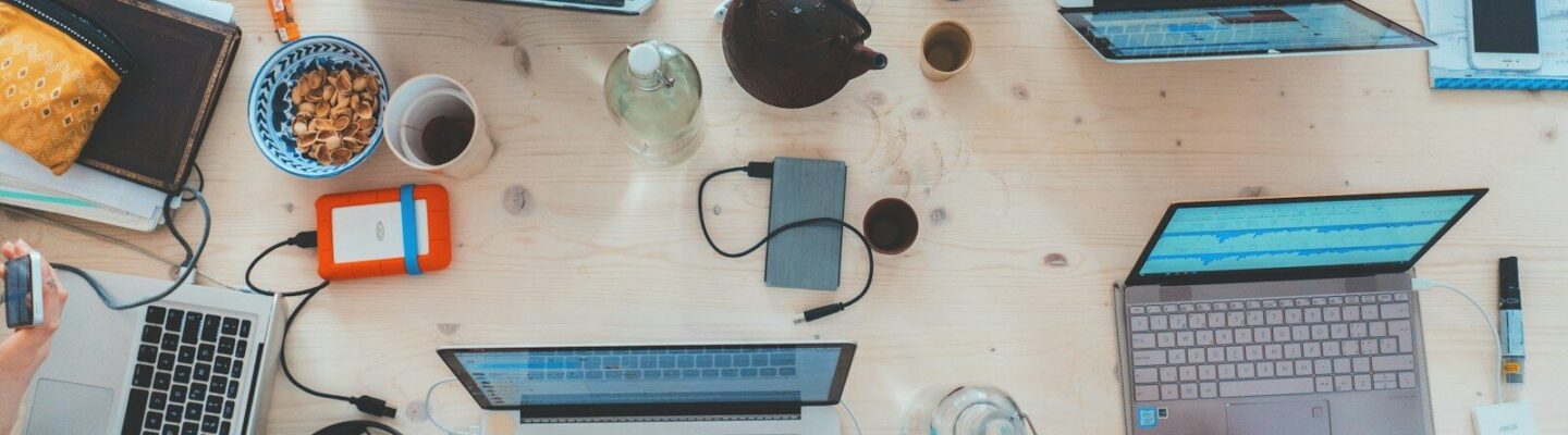 people sitting down near table with assorted laptop computers