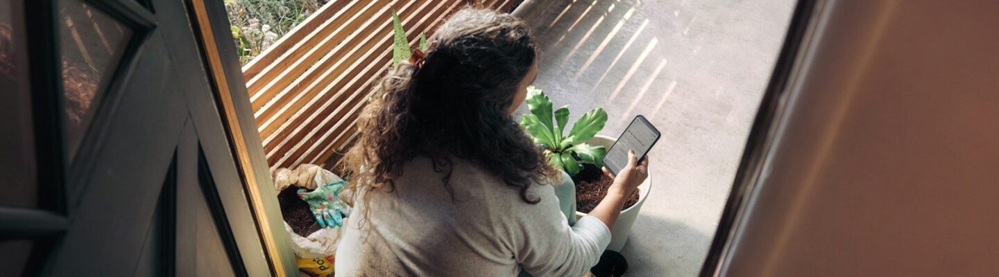 Woman sitting on balcony with smartphone