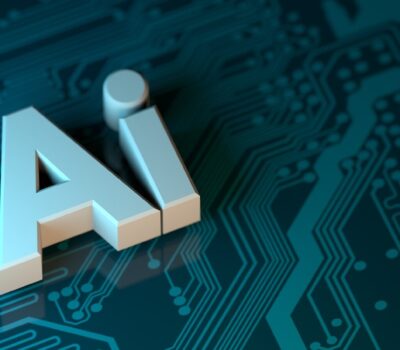 The letters AI in white 3D block font on a dark teal circuit board